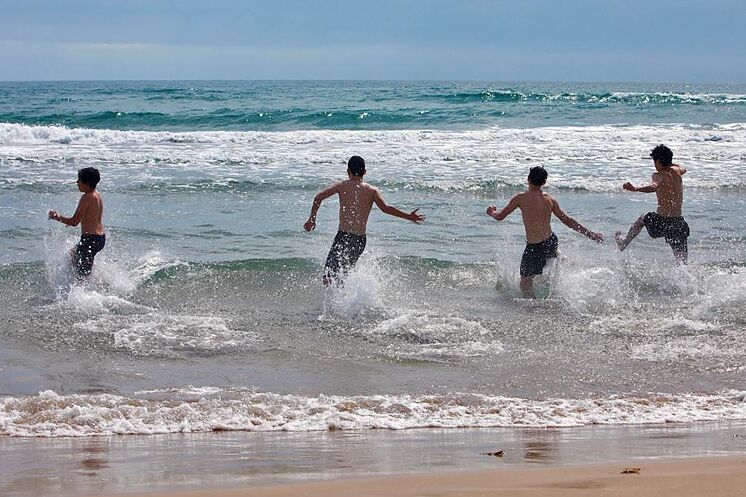 Varios jóvenes disfrutan del mar en la playa de Gandía (Valencia)ñ