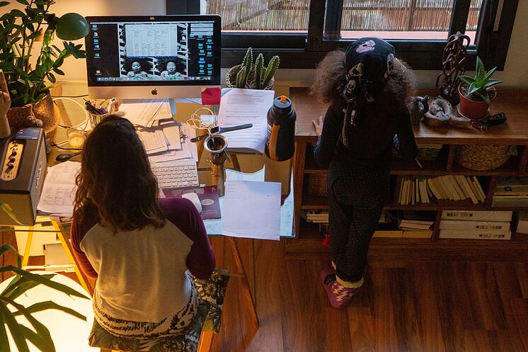 Una mujer teletrabaja con su hoja junto a ella.