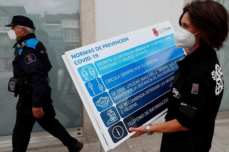 Une femme place un panneau d'information dans une rue de Viveiro (Lugo), ...