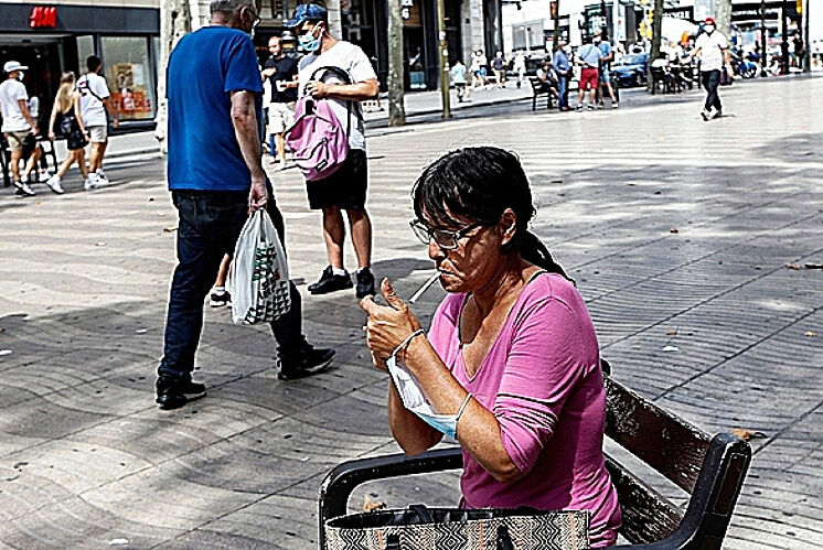 Une femme allume une cigarette sur les Ramblas de Barcelone.