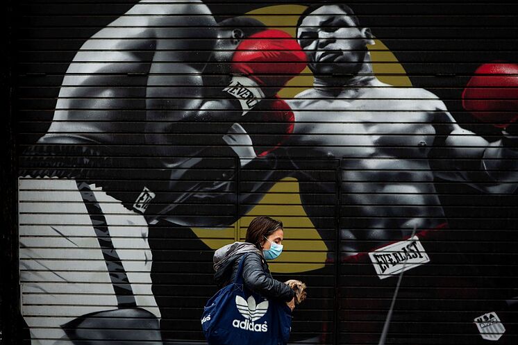 Une femme passe devant la porte d'une salle de sport fermée ...
