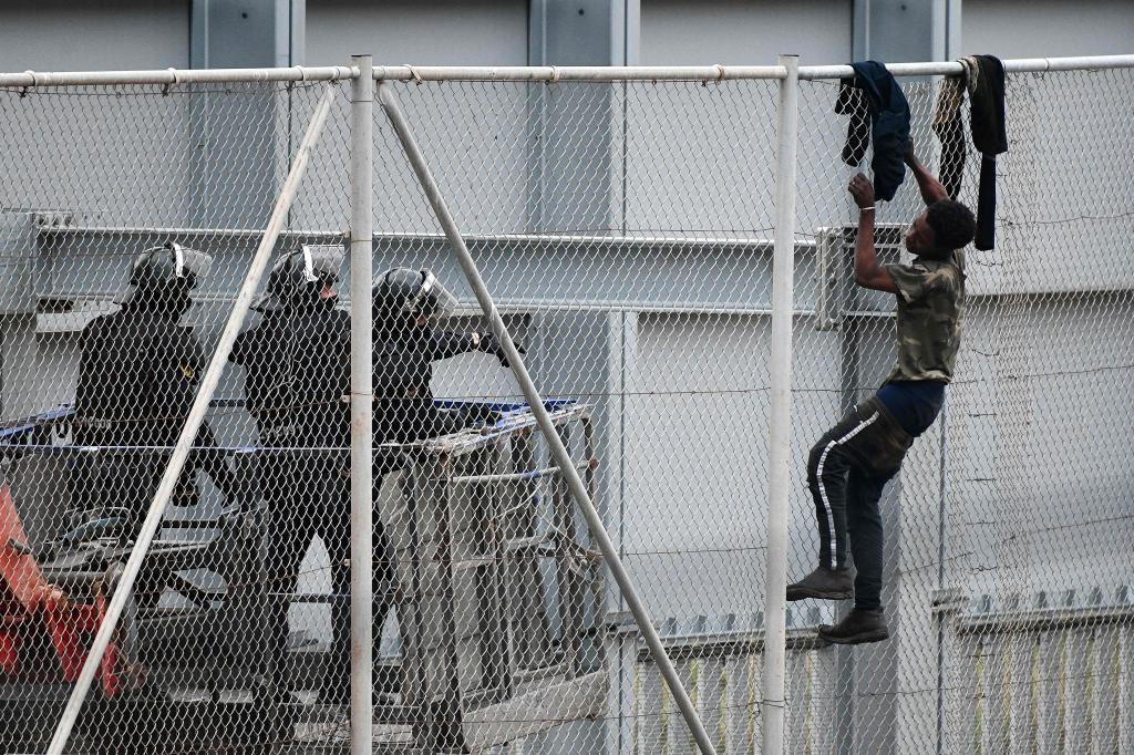 Un immigrant reçoit l'ordre de descendre de la barrière frontalière de Ceuta.