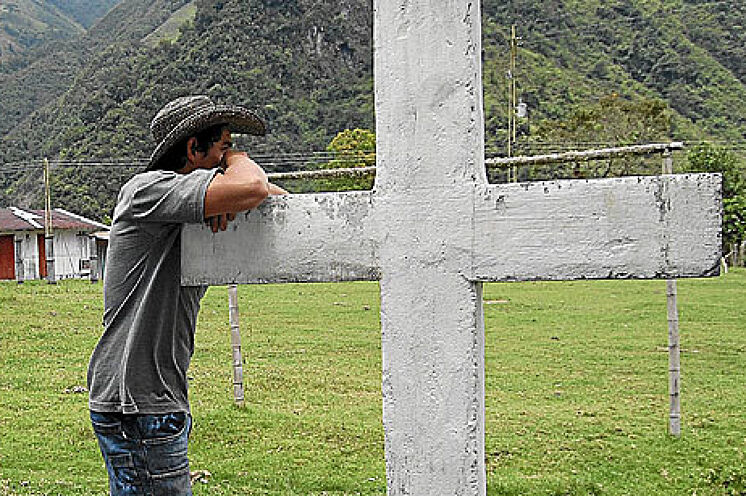 Un voisin de Puerto Brasil s'appuie sur une croix de pierre dans le village.