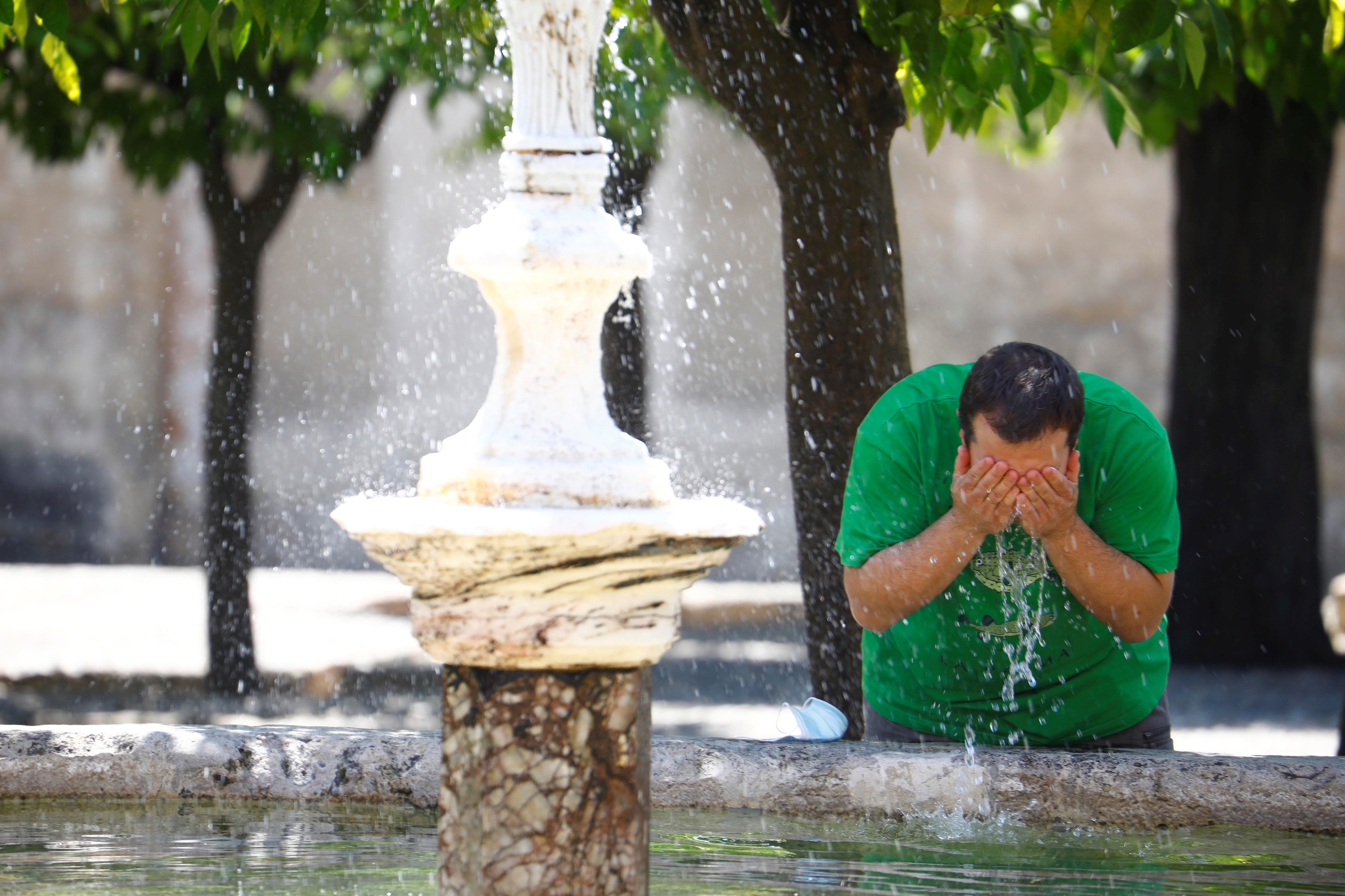 Un homme se rafraîchit dans la fontaine des orangers de la Mosquée - Cathédrale de C