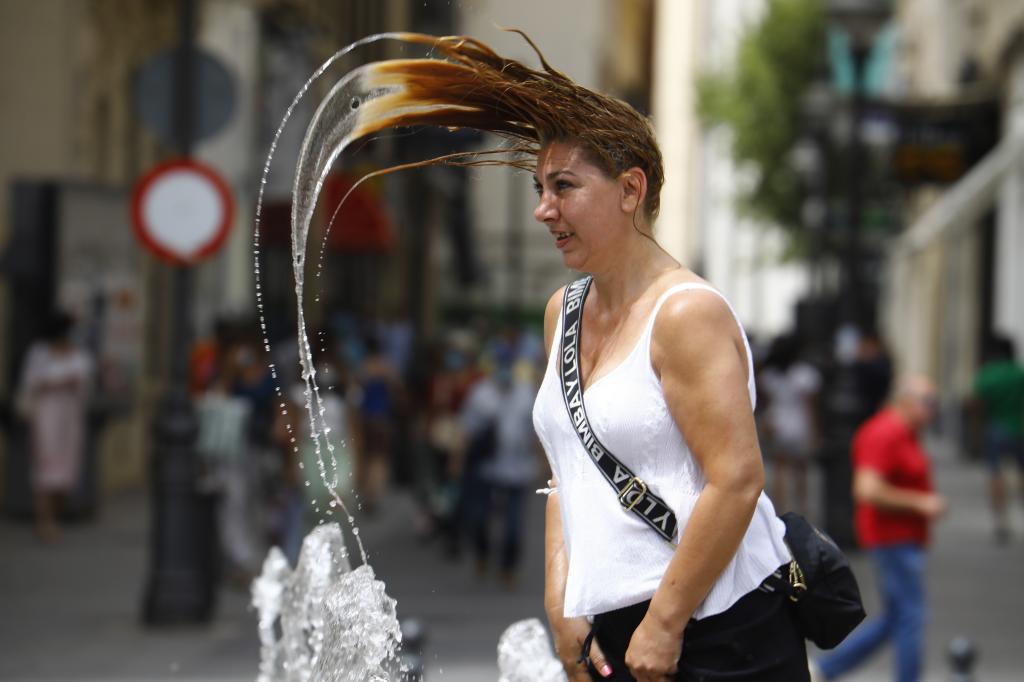 Une femme se rafraîchit dans une fontaine au centre-ville C
