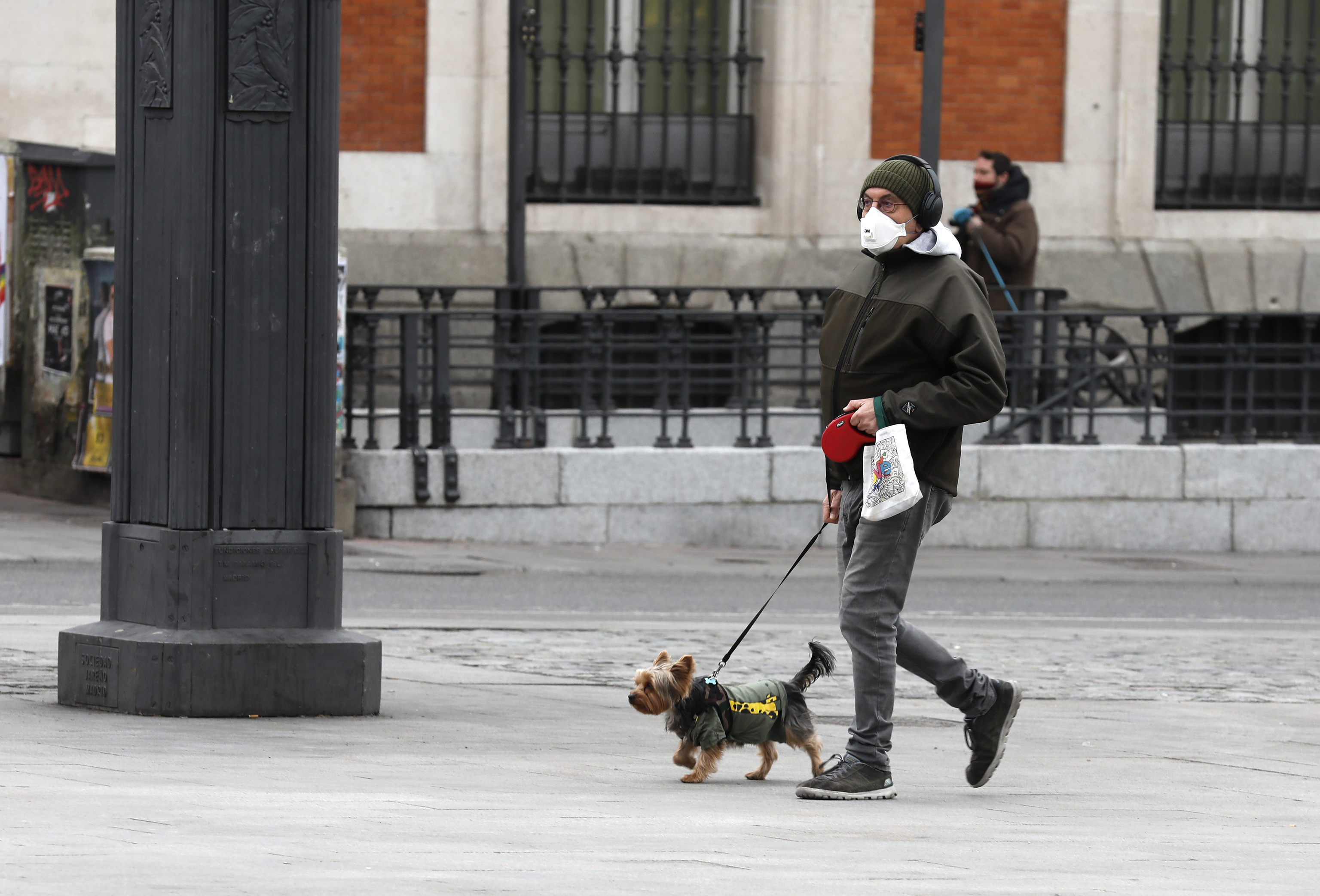 Un homme promène son chien dans le centre de Madrid.