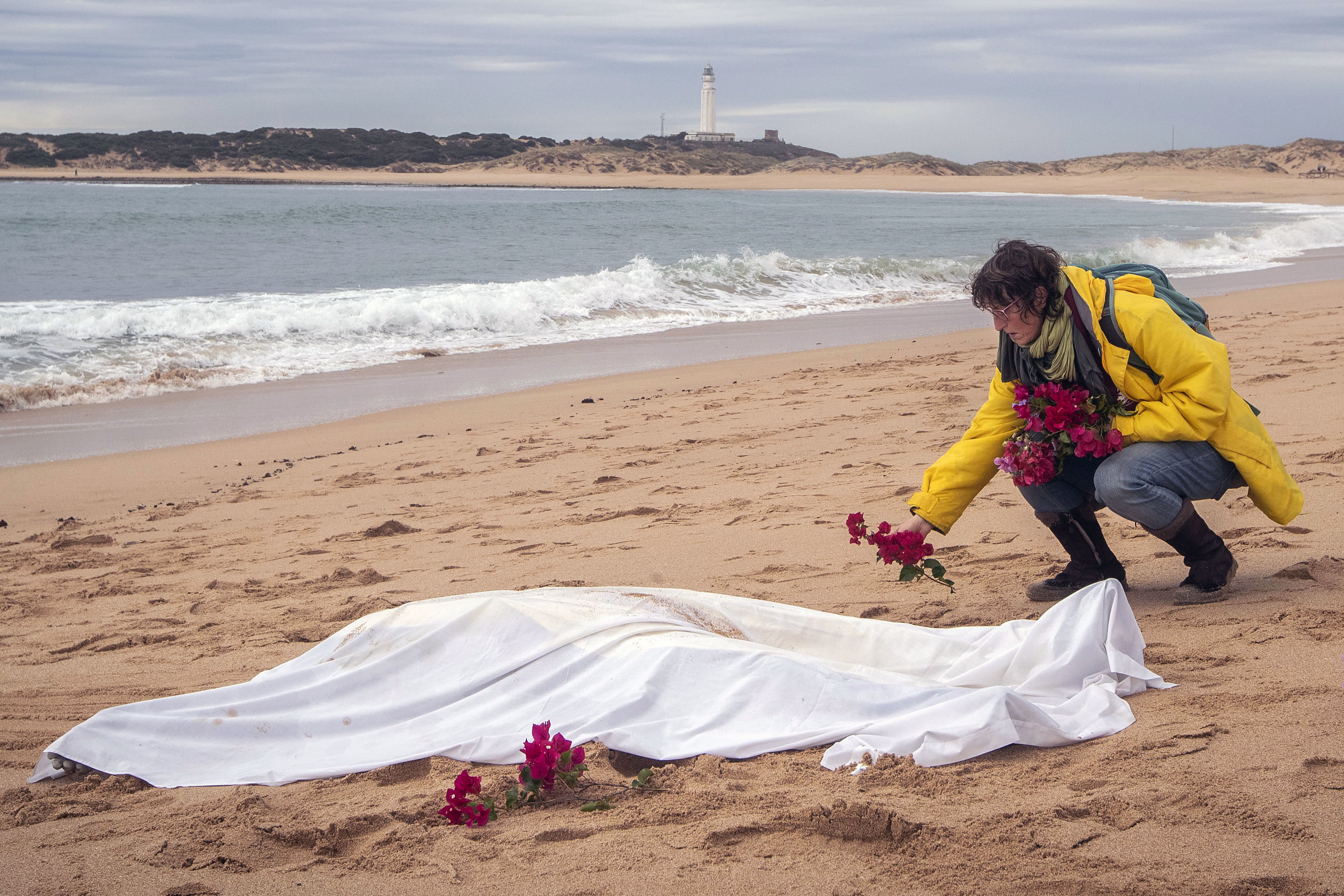 Une femme dépose des fleurs à côté du corps d'un immigrant traîné par l'eau.
