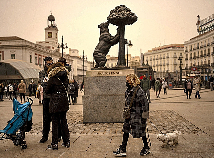 Les gens marchent alors que la tempête Celia souffle du sable du désert du Sahara sur la place Sol à Madrid, en Espagne.