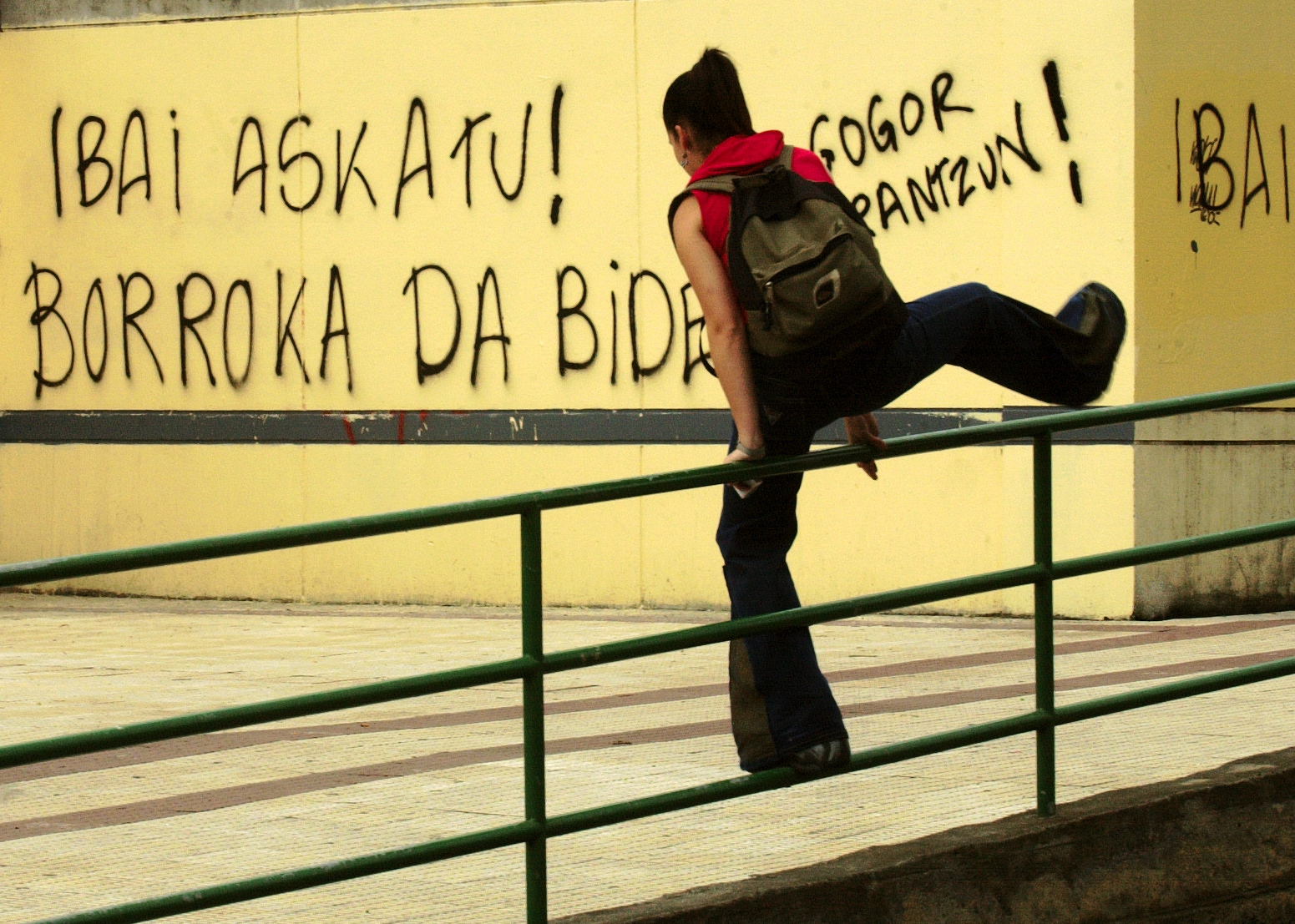 Une jeune femme saute par-dessus une balustrade avec des graffitis réalisés à Berango pour demander la liberté d'Aginaga lors de son arrestation.