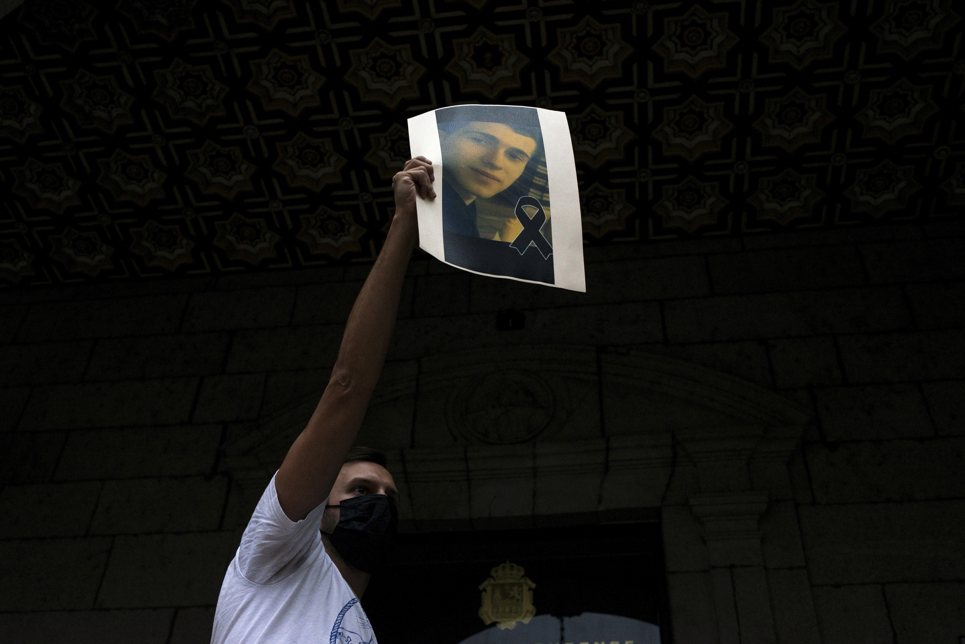 Un jeune homme montre une photo de Samuel Luiz lors d'un rassemblement