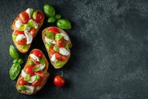 bruschetta-with-tomatoes-mozzarella-cheese-and-basil-on-a-dark-background-traditional-italian-appetizer-or-snack-antipasto-top-view-with-copy-space-flat-lay-2