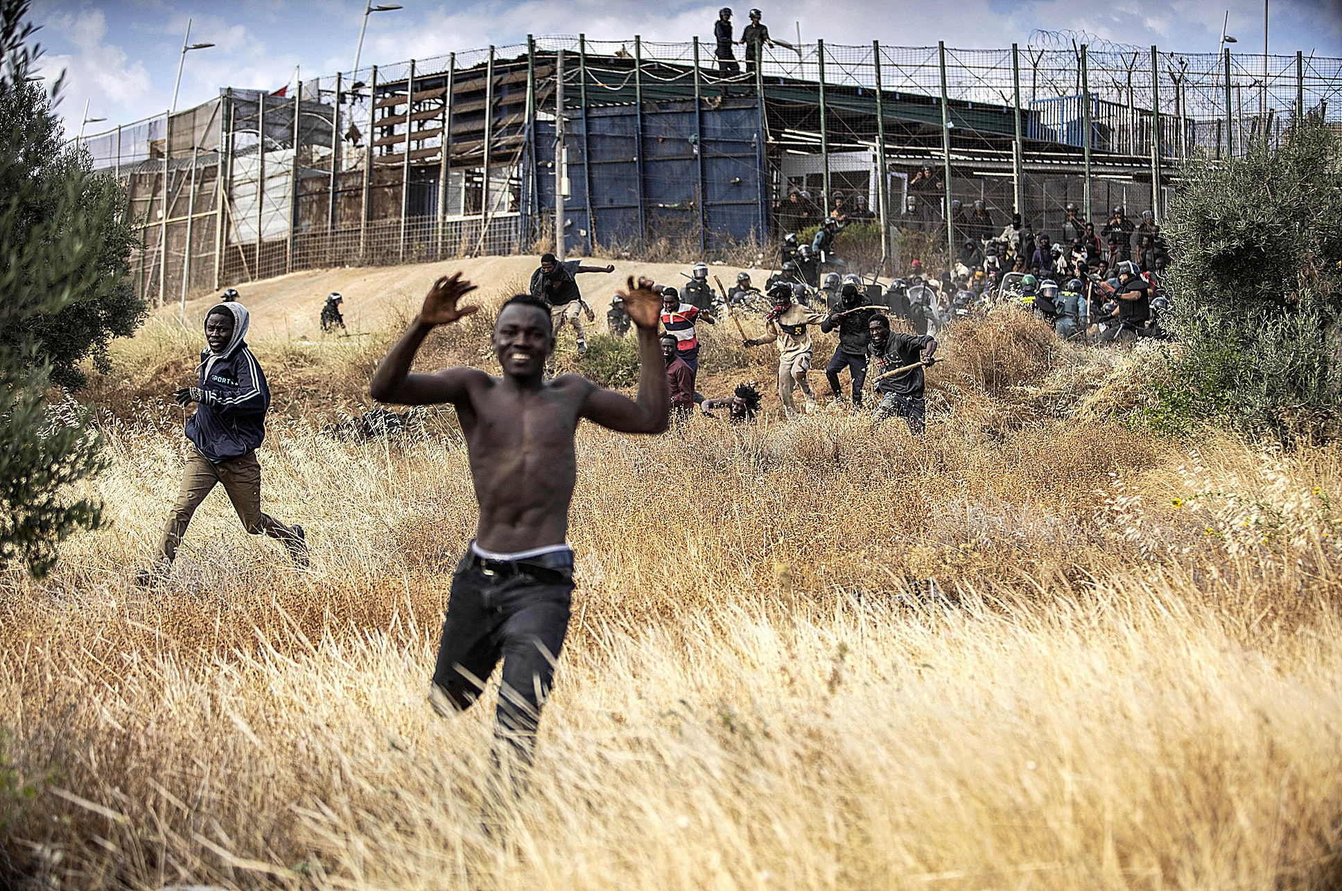 Un groupe d'immigrants célèbrent leur entrée à Melilla après avoir sauté la clôture.