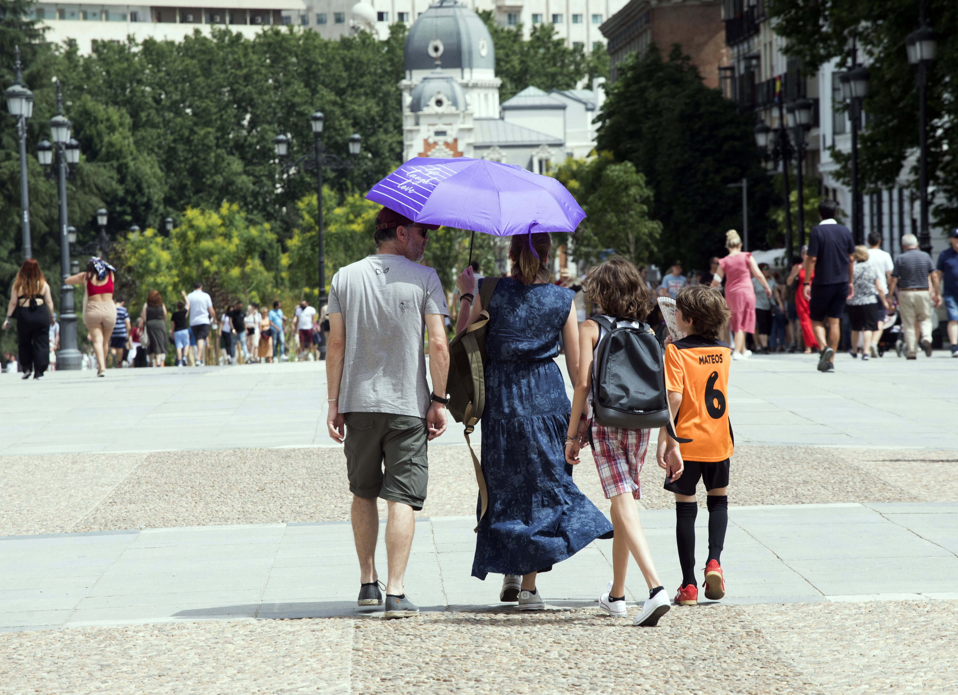 Une famille se protège du soleil avec un parapluie.