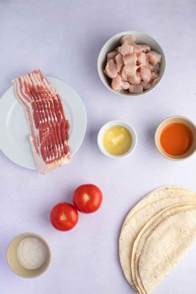 Ingrédients des ailes de poulet Buffalo - Bacon, poulet, sauce pour ailes Buffalo, beurre, tortillas à la farine, vinaigrette ranch et tomates