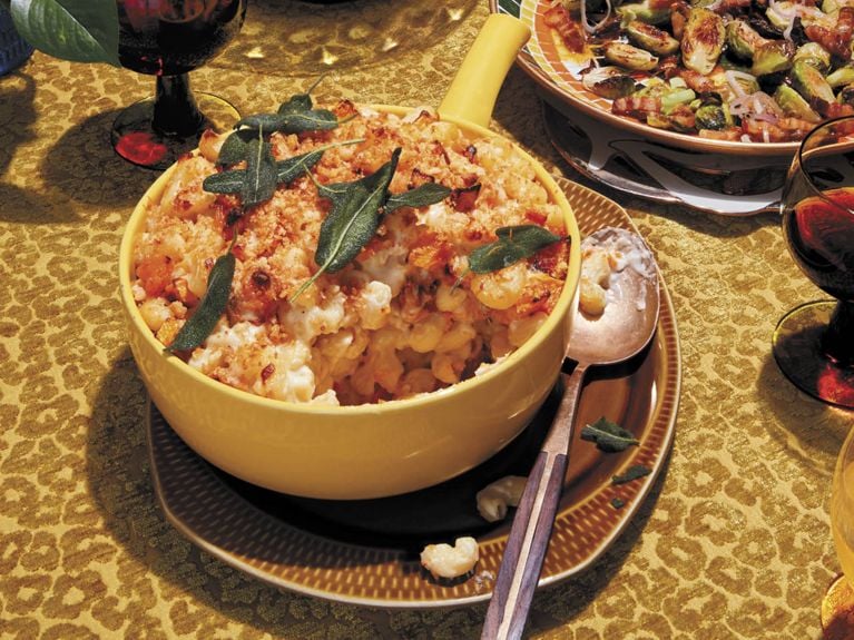 Un grand bol de macaroni au fromage avec de la courge musquée garnie de sauge croustillante servi dans le cadre d'une tartinade de Thanksgiving