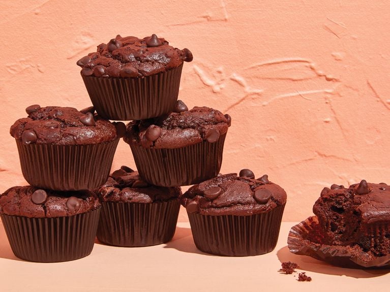 Muffins végétaliens à l'orange et aux canneberges empilés à côté d'un muffin partiellement mangé