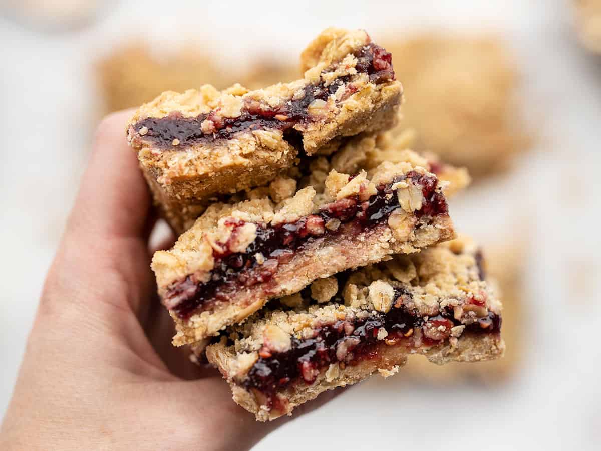 Une main tenant une pile de barres d'avoine à la framboise près de la caméra