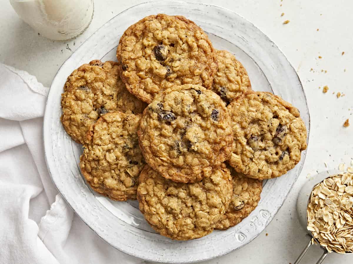 Vue aérienne d'une pile de biscuits à l'avoine sur une assiette avec une serviette blanche et une tasse de lait sur le côté.