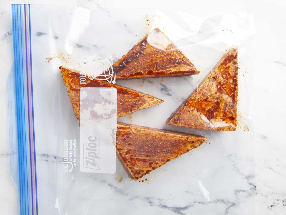 Triangles de tofu BBQ marinés dans un sac Ziploc pour la congélation.