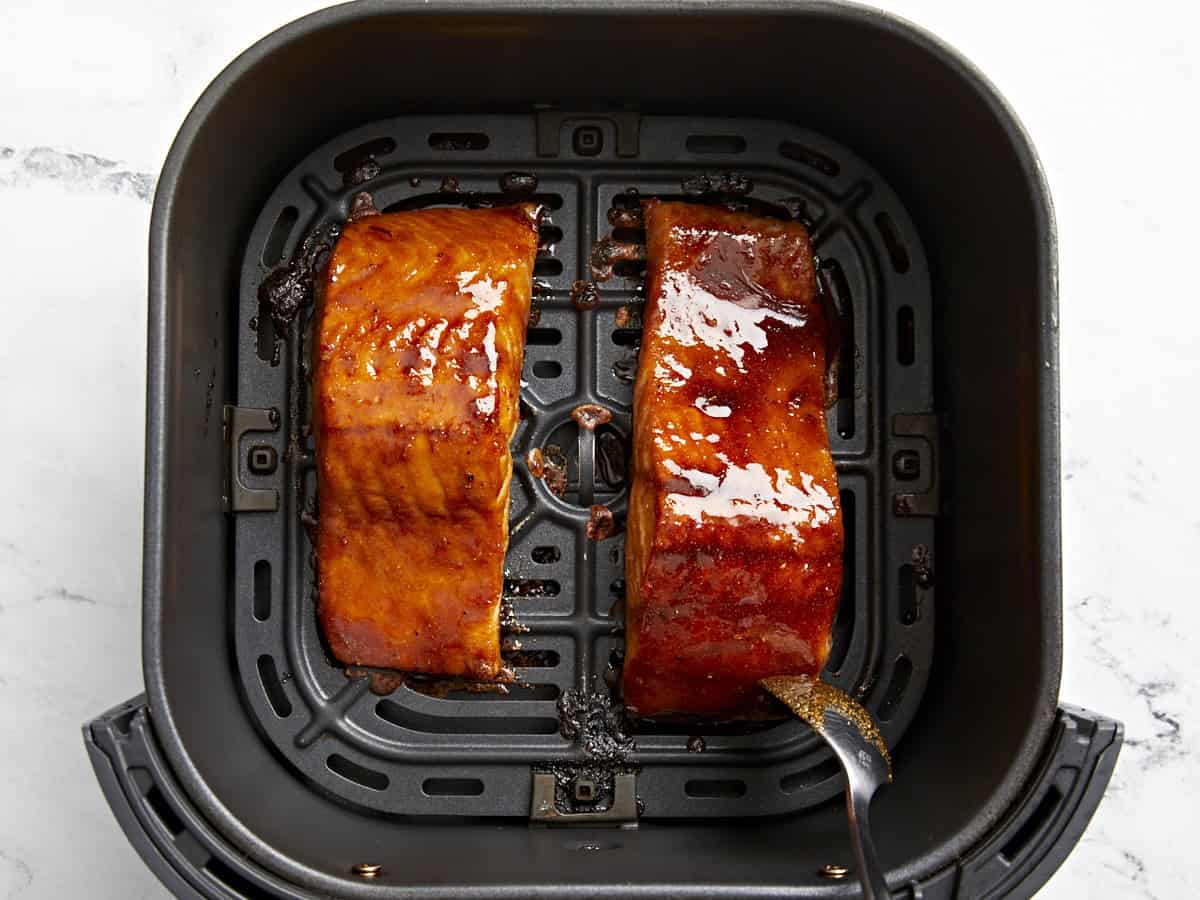 verser la marinade sur des filets de saumon partiellement cuits dans un panier de friteuse à air.