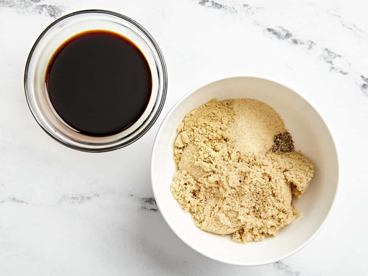 cassonade et assaisonnements dans un bol blanc à côté d'un plat en verre contenant de la sauce soja.