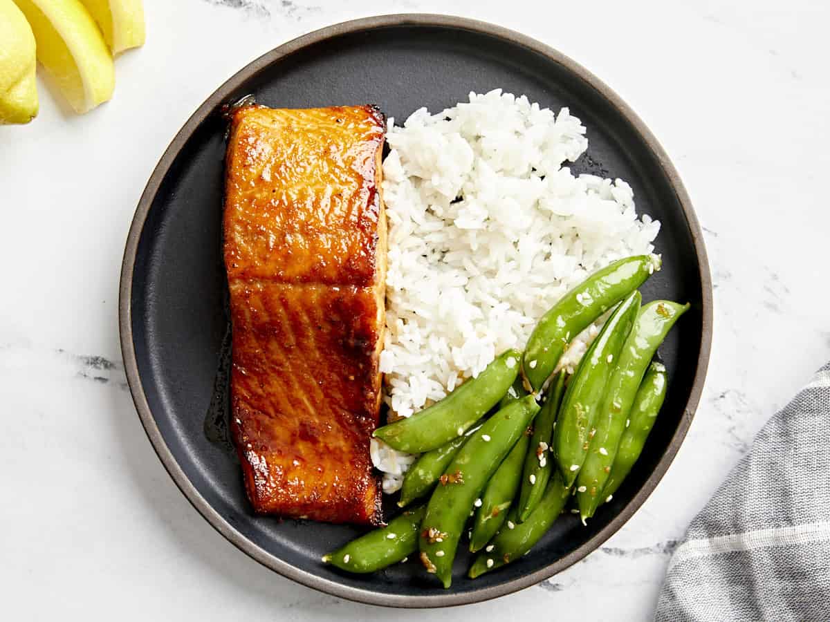 vue aérienne d'une portion de saumon à la friteuse à air sur une assiette noire avec du riz et des pois.