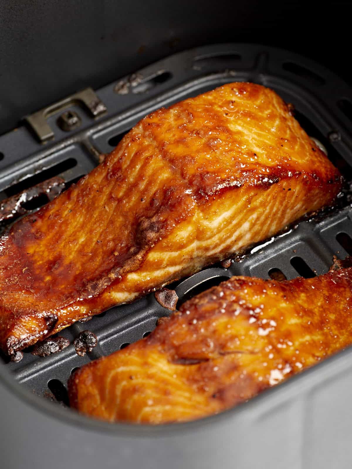 gros plan de filets de saumon cuits à la friteuse à air dans un panier de friteuse à air.