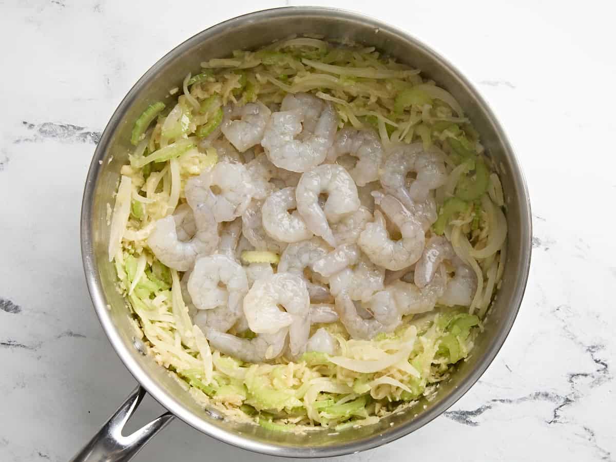 Crevettes crues ajoutées à une poêle avec mirepoix blanc pour crevettes et haricots blancs