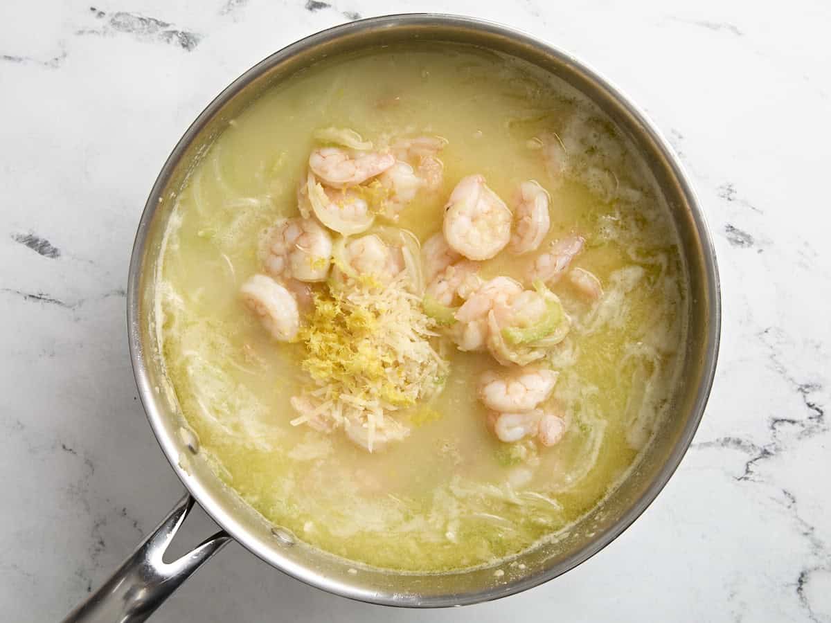 ragoût de crevettes et de haricots blancs dans une poêle avec du zeste de citron ajouté