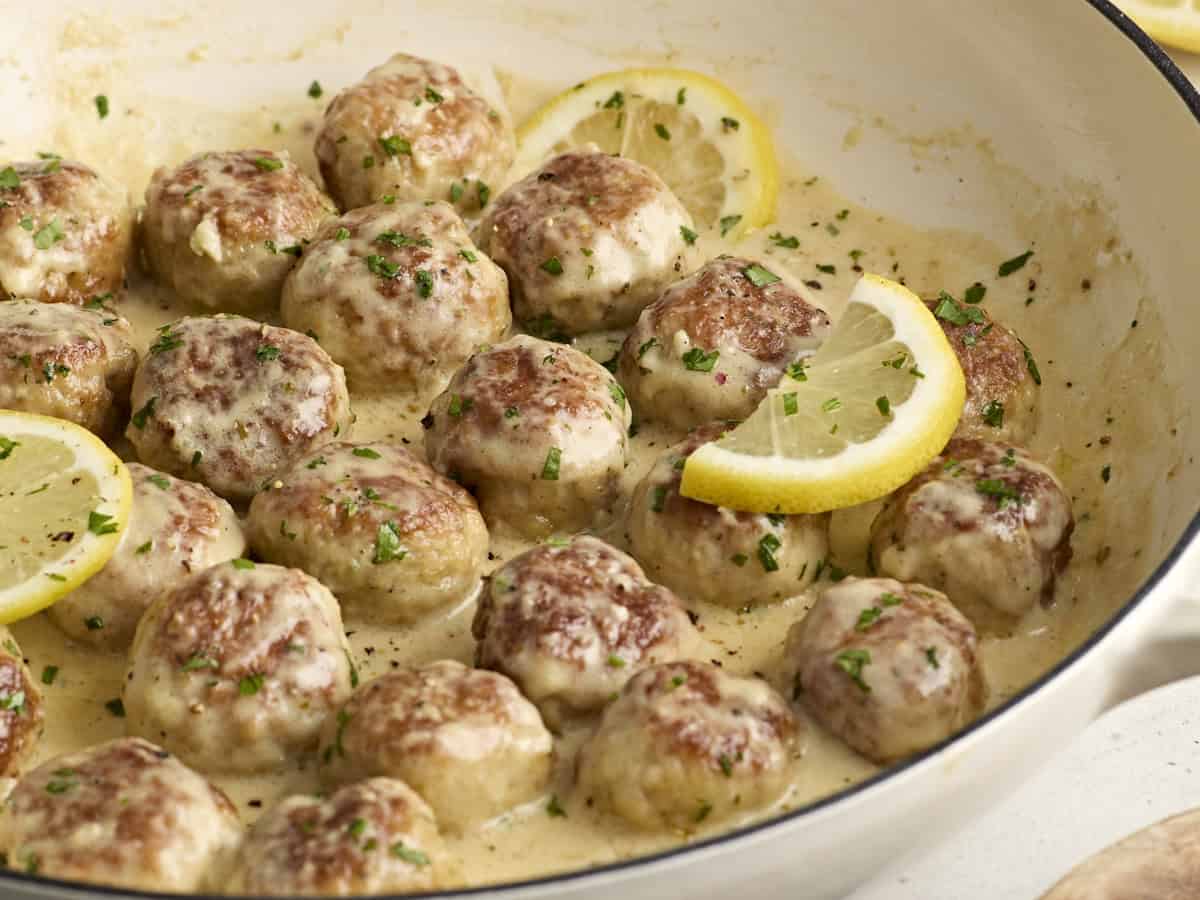 Vue latérale de boulettes de poulet dans une grande poêle avec sauce à la crème.
