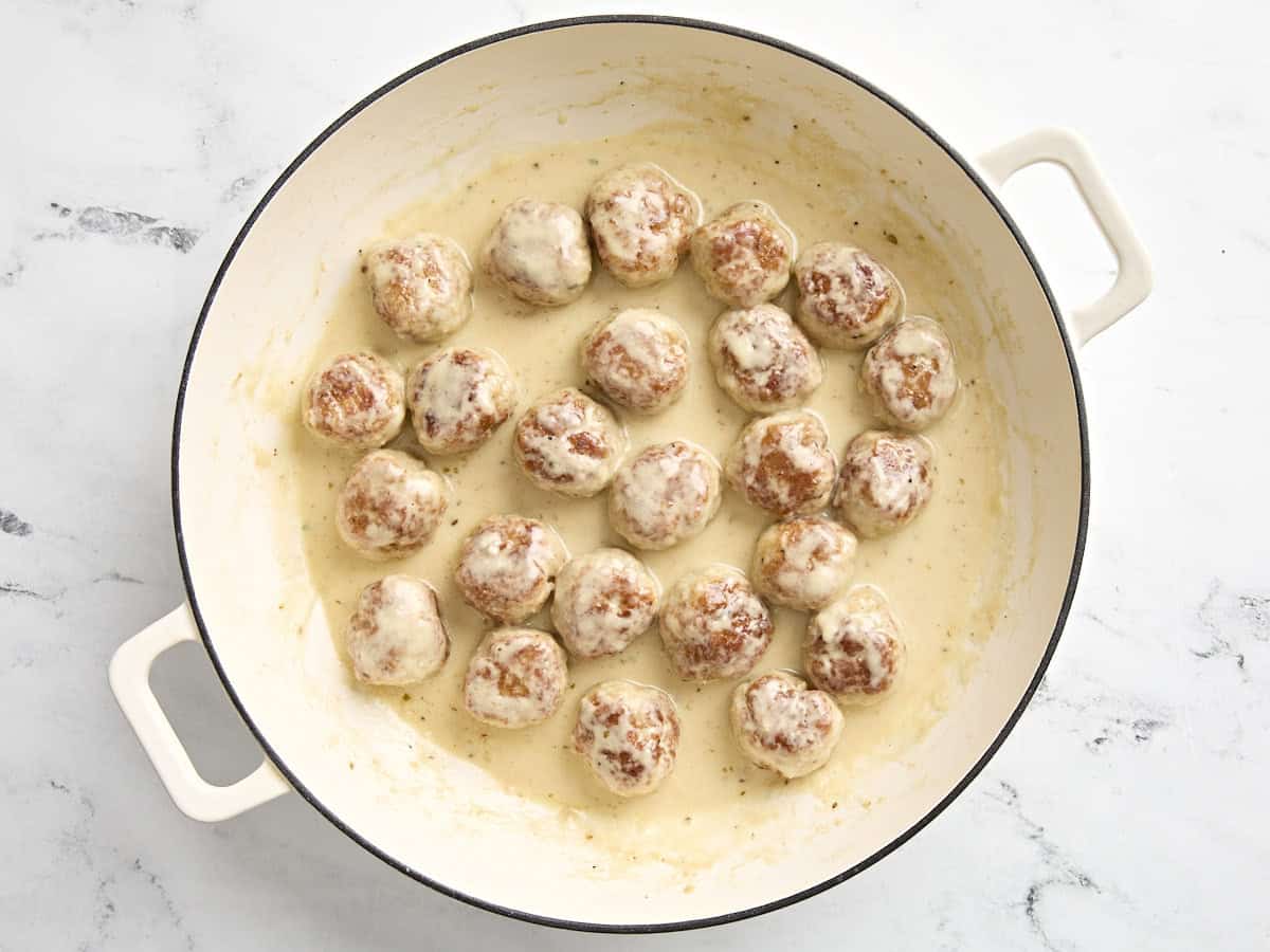 boulettes de poulet remises dans la poêle avec une sauce à la crème.