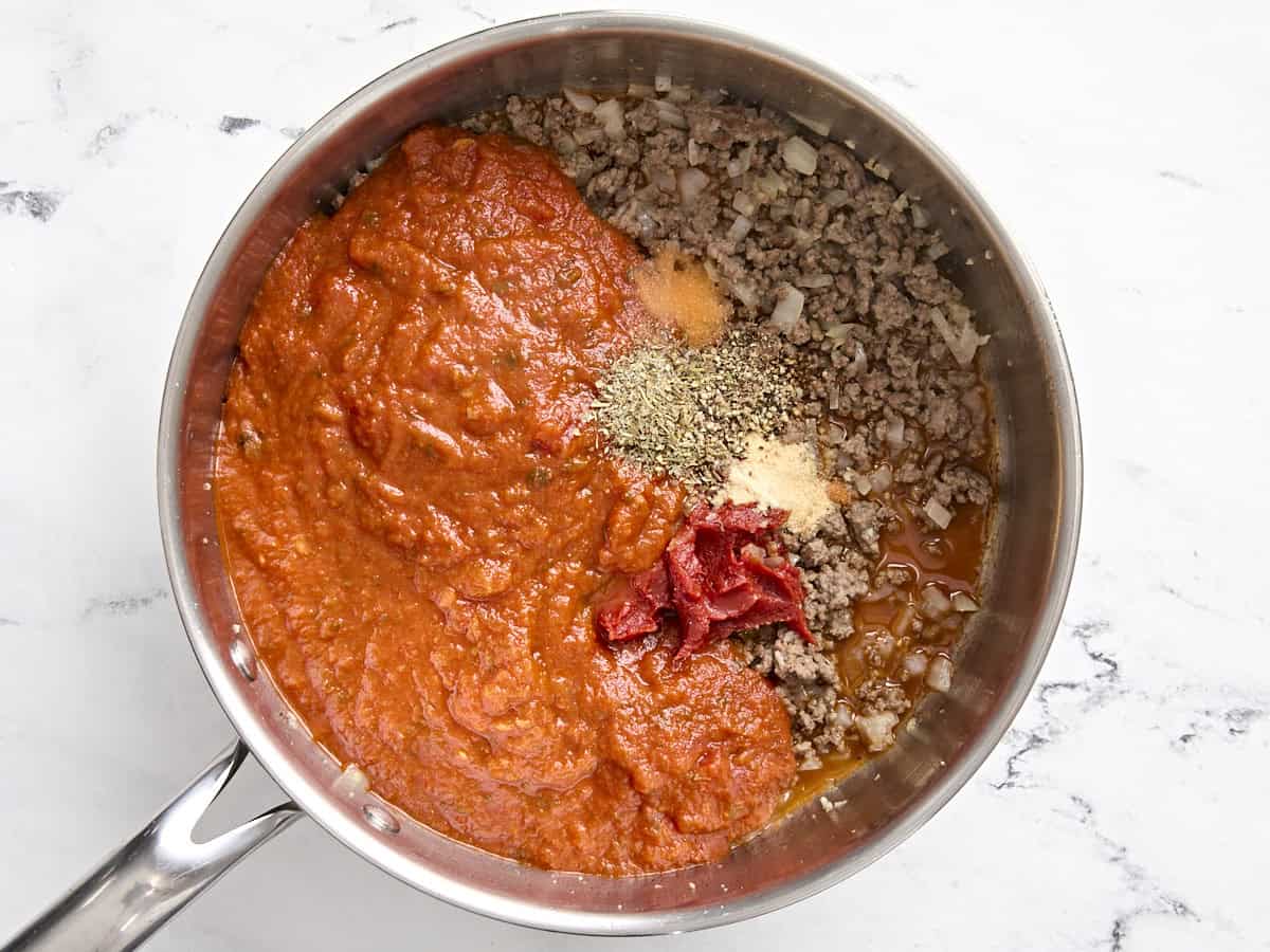 Sauce marinara, pâte de tomate et épices ajoutées au bœuf dans une poêle.