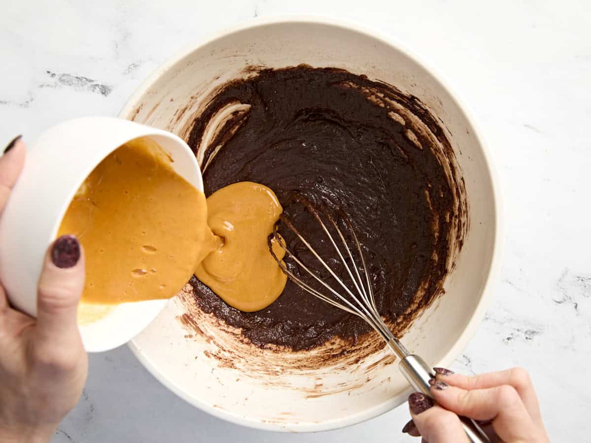 Purée de citrouille et mélange d'œufs versés dans la pâte à brownie dans un plat allant au four.