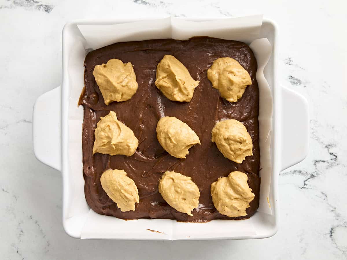 Pâte à brownie à la citrouille garnie de cuillerées de garniture au fromage à la crème à la citrouille.