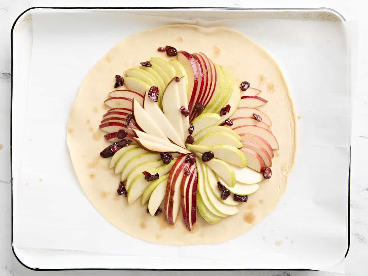 Poires tranchées et canneberges séchées sur un fond de tarte préfabriqué non cuit pour galette de poires.