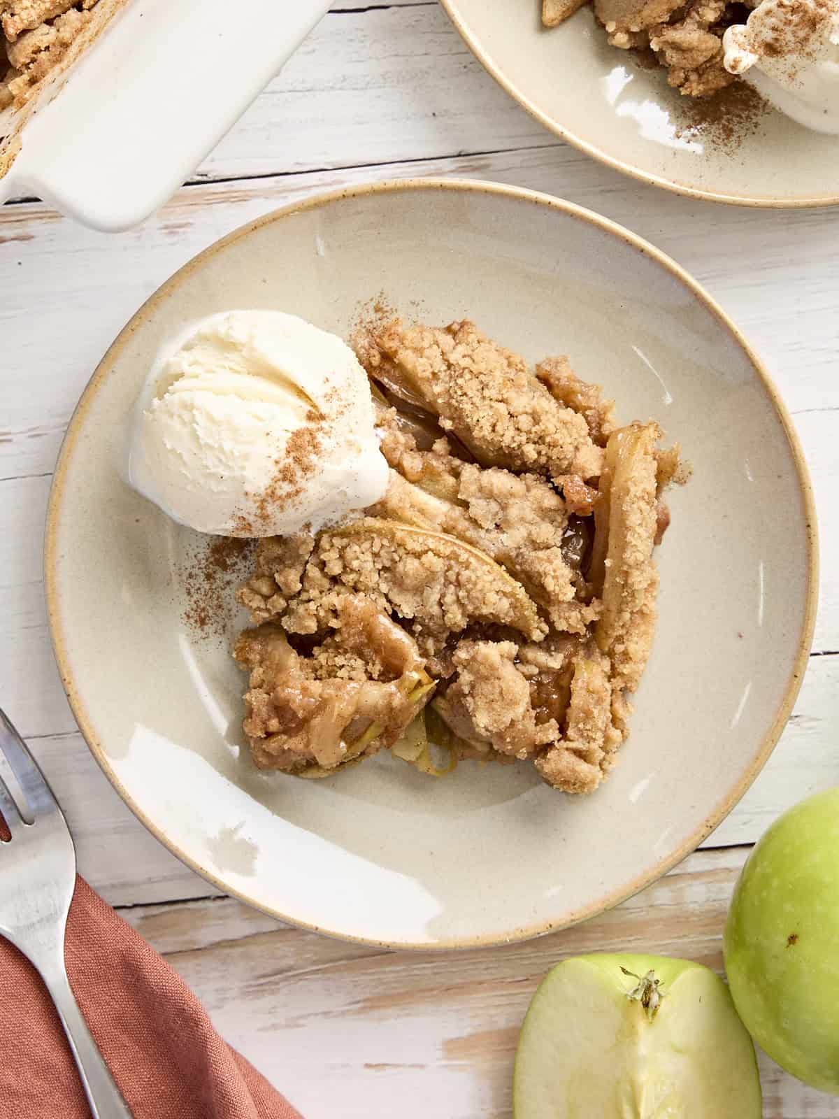 Vue aérienne du crumble aux pommes sur une assiette avec une boule de glace à la vanille.