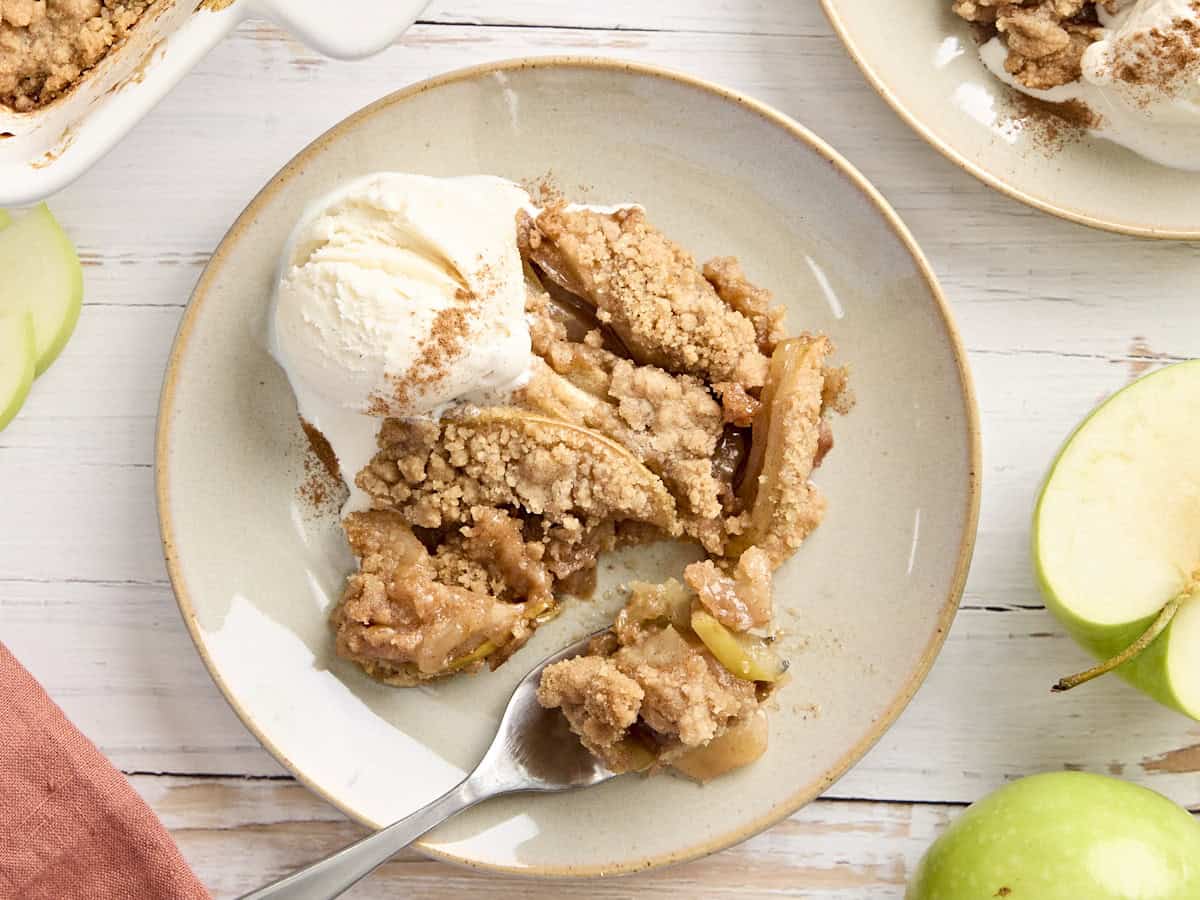Vue aérienne du crumble aux pommes et d'une boule de glace à la vanille sur une assiette avec une fourchette en prenant.