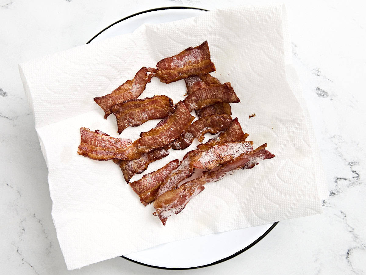 Bacon cuit croustillant sur une assiette tapissée de papier absorbant.