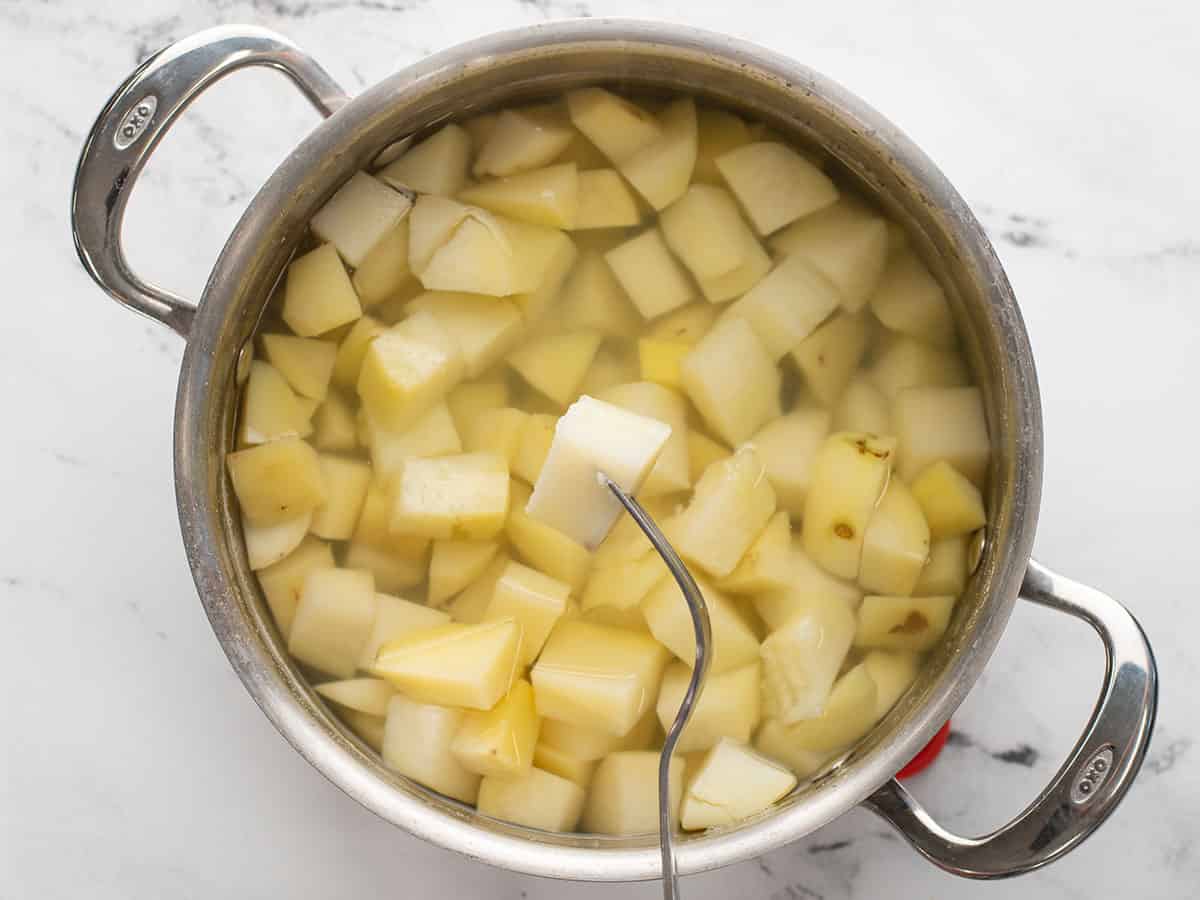 Une fourchette perçant une pomme de terre du pot.