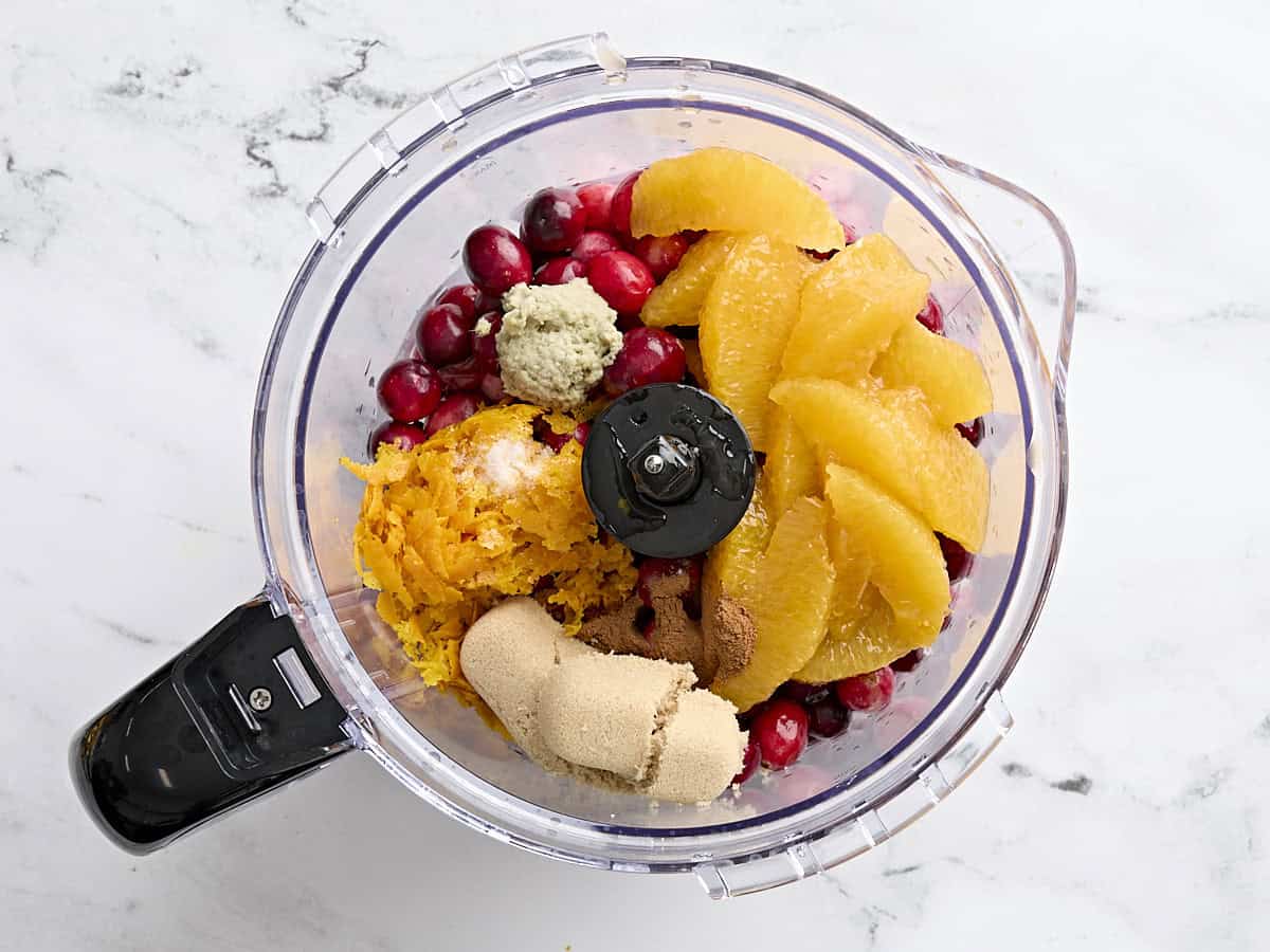 Canneberges, quartiers d'orange, zeste d'orange, cassonade, gingembre et cannelle dans un robot culinaire.