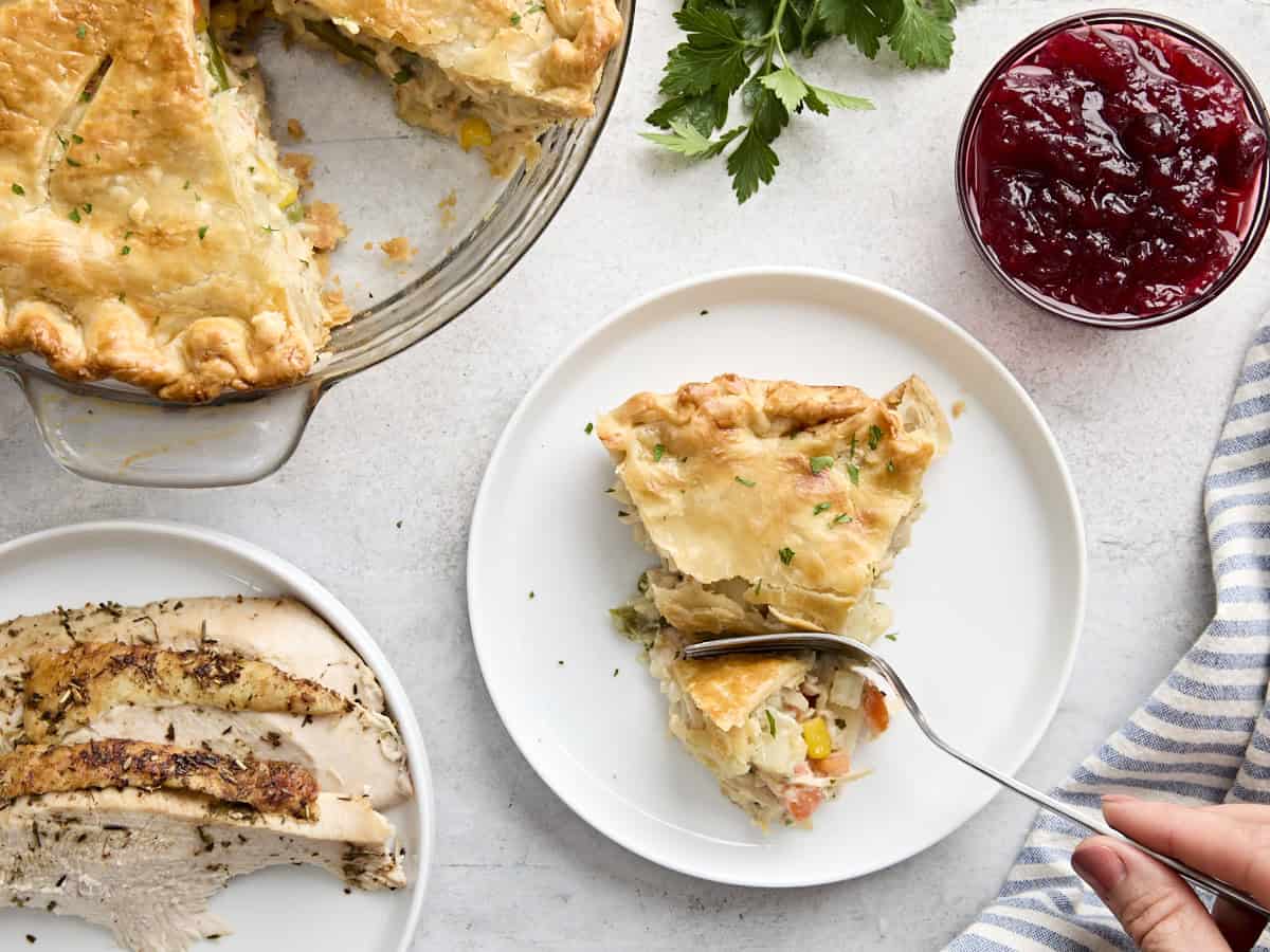 Vue aérienne d'une fourchette creusant dans une tranche de tourte à la dinde sur une assiette.