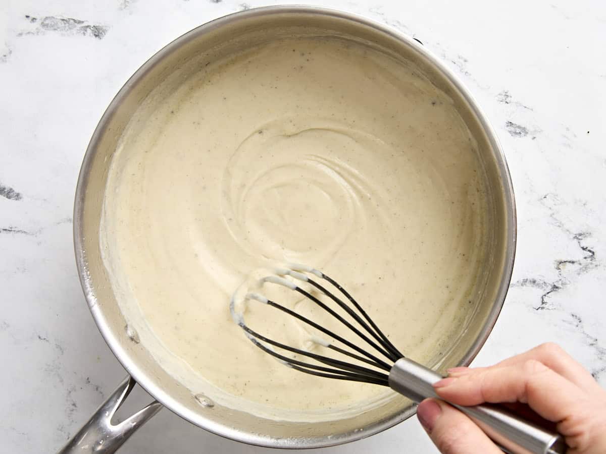 Une main fouettant la sauce pour la tourte à la dinde.
