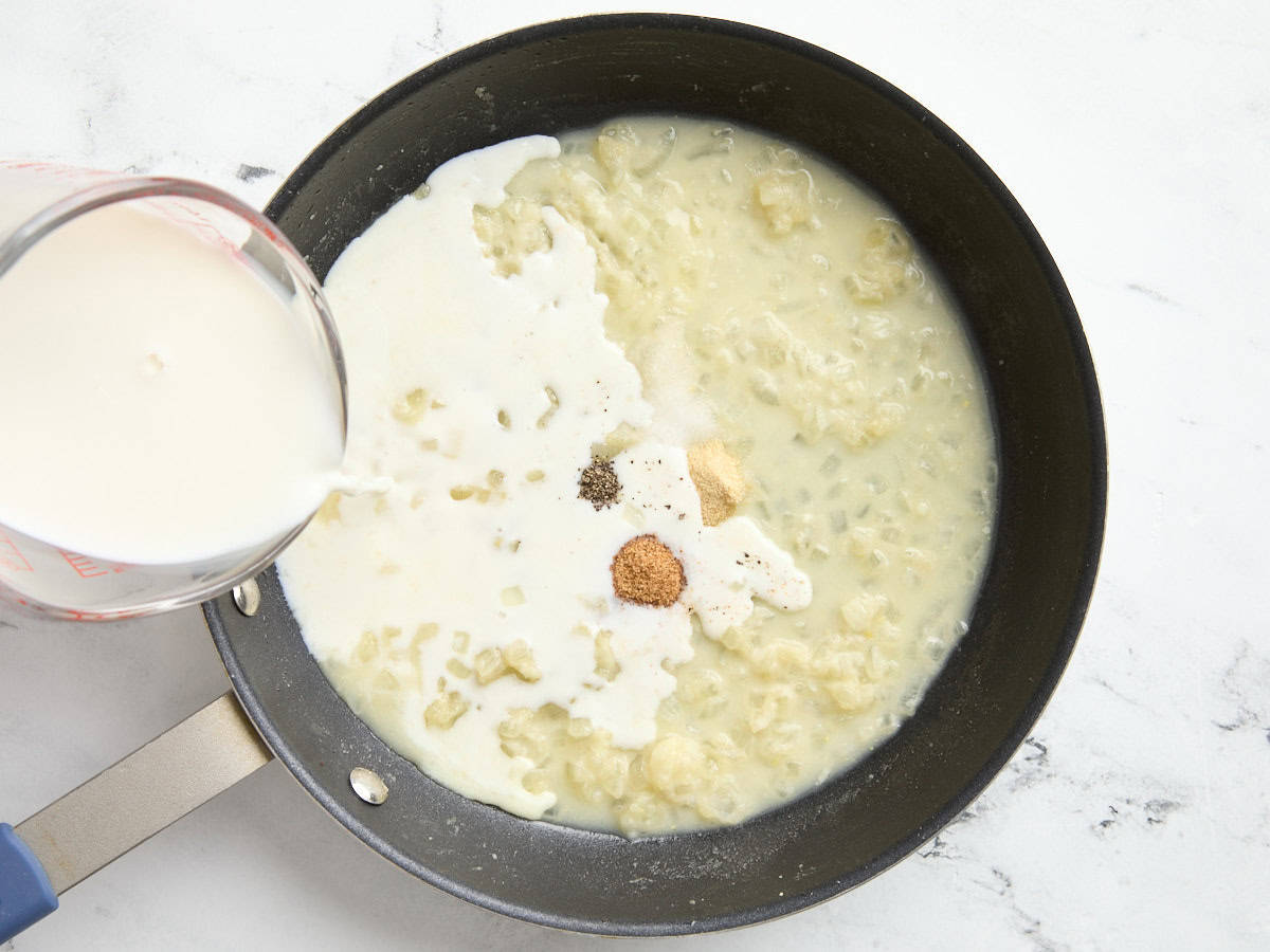 Le lait est versé dans une poêle avec des oignons coupés en dés.