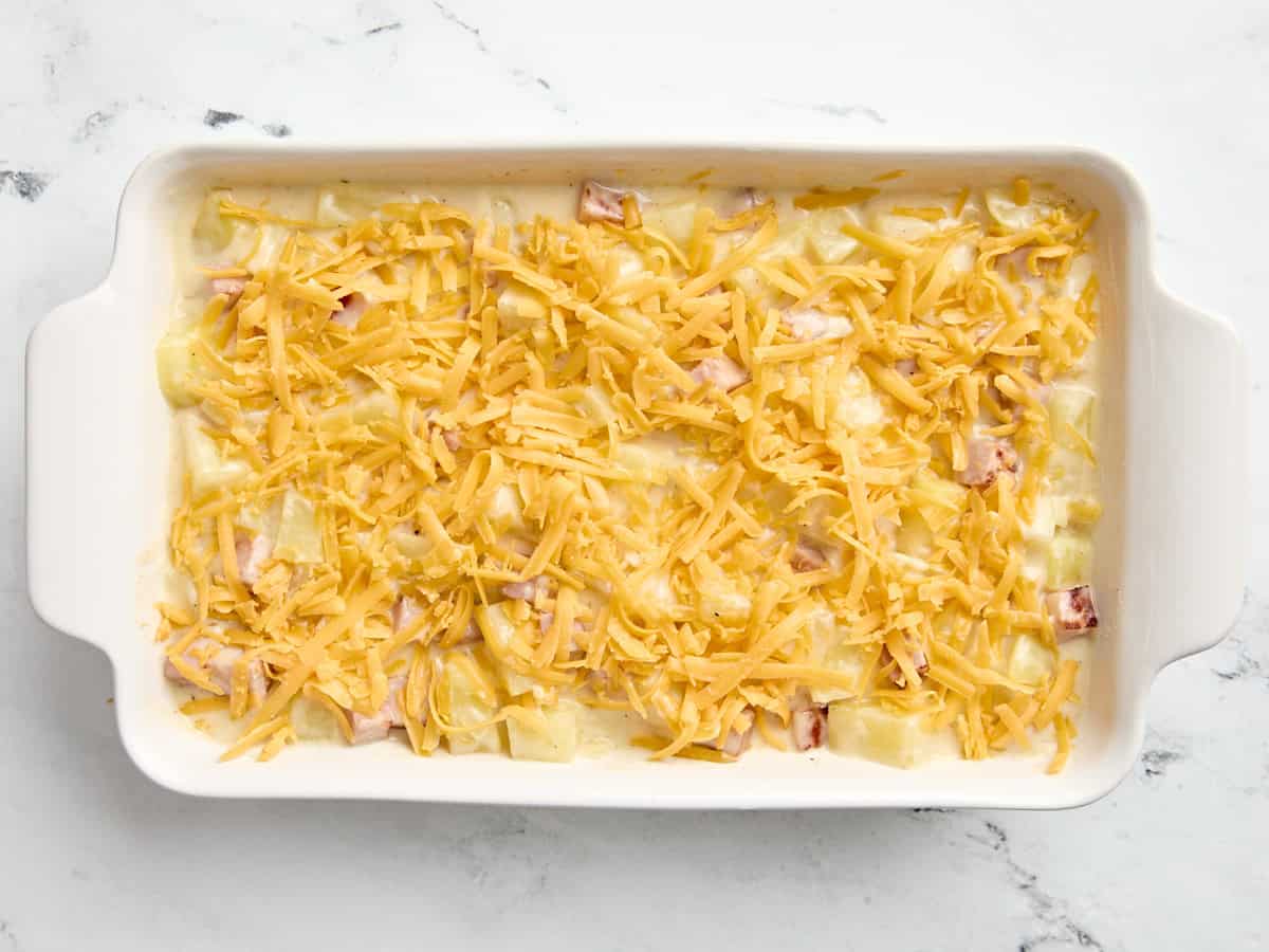 Casserole de jambon et de pommes de terre garnie de fromage râpé dans une cocotte.