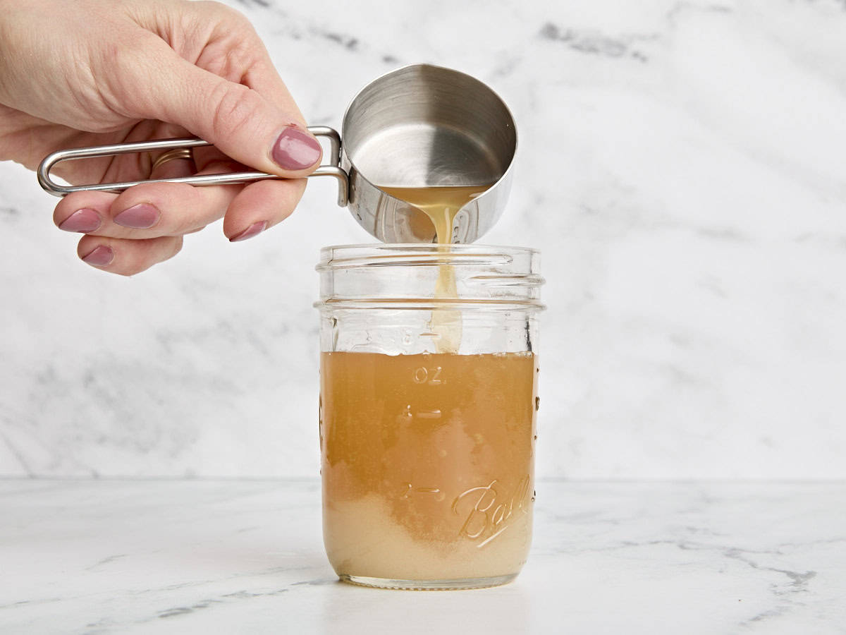 Cidre de pomme versé dans du vinaigre et du sucre dans un pot Mason.