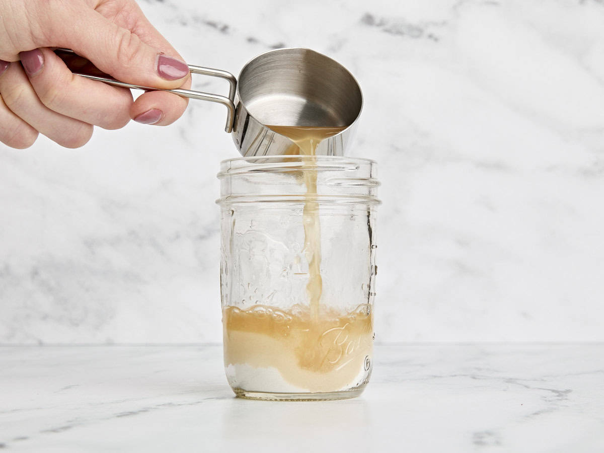 Vinaigre de cidre de pomme versé dans du sucre cristallisé dans un pot Mason.