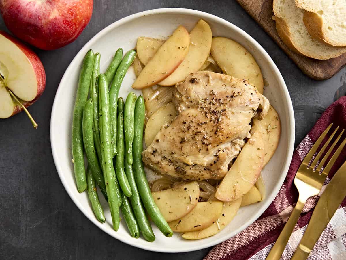 Vue aérienne du dîner à la poêle de poulet et de pommes sur une assiette de haricots verts.