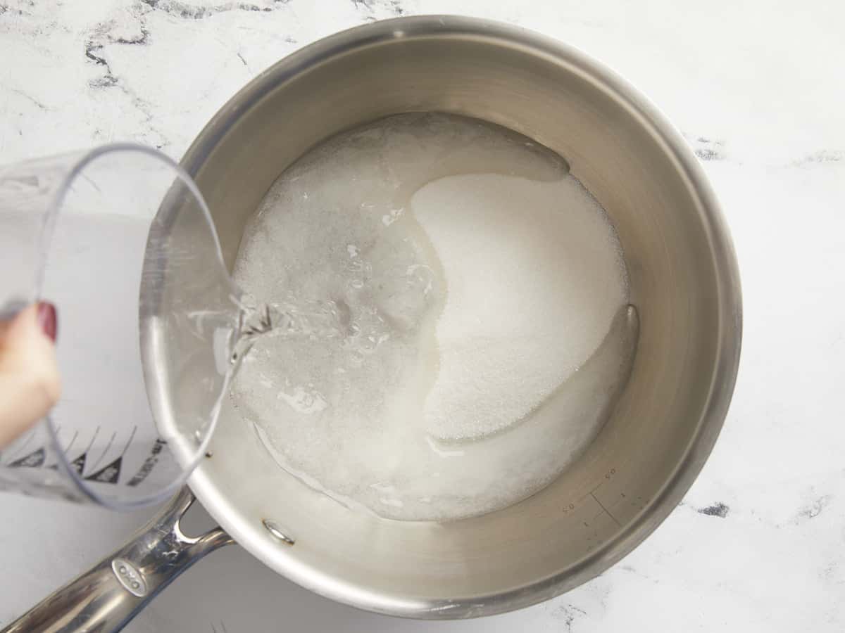 De l'eau est versée dans une casserole avec du sucre.