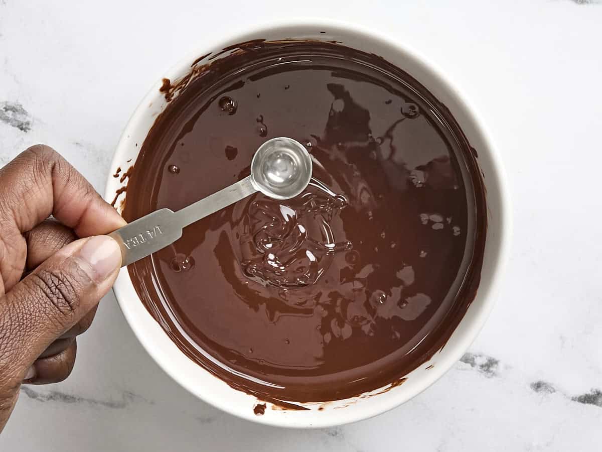 Extrait de menthe poivrée ajouté à un bol de chocolat fondu.