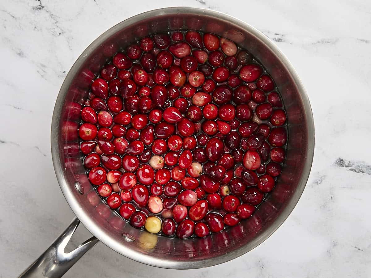 Canneberges fraîches dans une casserole d'eau sucrée.
